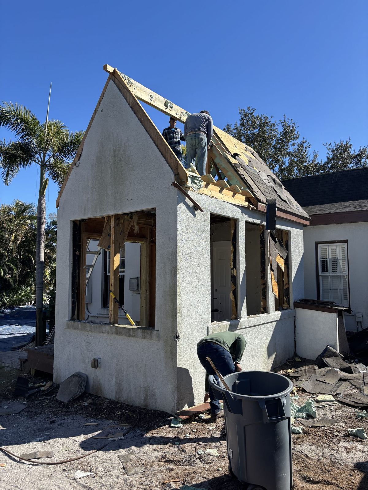 Crew tearing off roof and frame of the addition