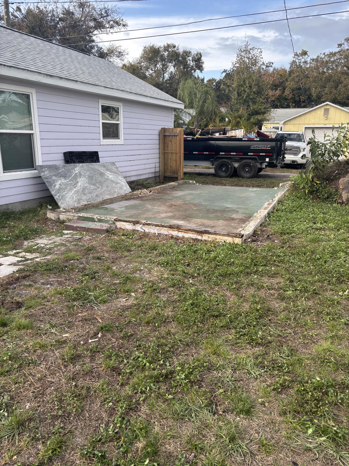 A cleared slab and a loaded debris trailer after a full home teardown by Griffin Demolition